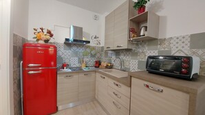 A kitchen with a red refrigerator, a toaster, and a shelf with a plant. - LOFT HISTORICAL CENTER CATANIA WITH PRIVATE COURTYARD (Catania)