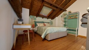 A bedroom with a wooden ceiling, a bed with a light-colored bedspread, a desk with a chair, and a green wardrobe. - LOFT HISTORICAL CENTER CATANIA WITH PRIVATE COURTYARD (Catania)