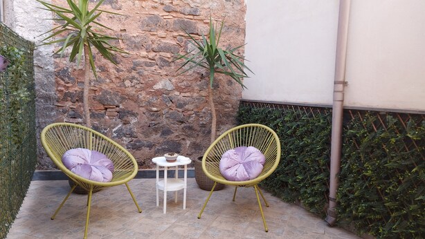 Two wicker chairs with cushions, a small table, and a stone wall in a courtyard. - LOFT HISTORICAL CENTER CATANIA WITH PRIVATE COURTYARD (Catania)