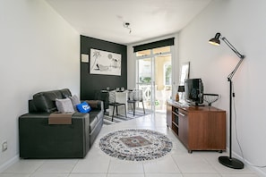 A modern living room with a dark sofa, a coffee table, a TV, and a floor lamp.