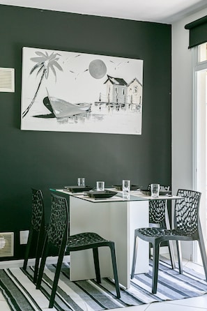 A dining area with a table, chairs, and a wall-mounted painting.