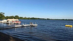 A calm lake with boats docked at a pier, surrounded by trees.