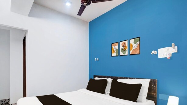 A hotel room with a bed, a nightstand with a lamp, a phone, and a ceiling fan. - Hotel O Noonmati Guwahati (Guwahati)