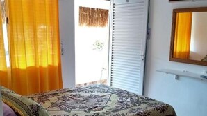 Une chambre à coucher avec un lit, un ventilateur, une télévision et une fenêtre avec des rideaux.