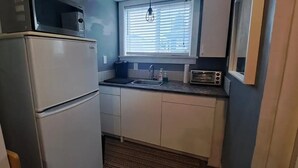 A compact kitchen with a refrigerator, microwave, toaster, sink, and window with blinds. - Cozy Private Guest Suite Near SkyTrain (New Westminster)