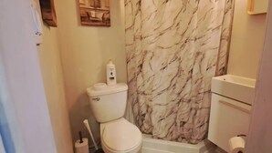 A bathroom with a toilet, a shower curtain, and a bottle of Dove body wash. - Cozy Private Guest Suite Near SkyTrain (New Westminster)