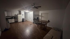 Eine kompakte Küche mit weißen Schränken, einem Kühlschrank und einem Essbereich mit Tisch und Stühlen.