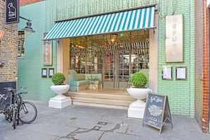 A building with a green facade, a striped awning, and a sign that reads 'REFUEL BAR & RESTAURANT.' - Superb Fitzrovia Regent Street 3 Bed 3 Bath WiFi (London)