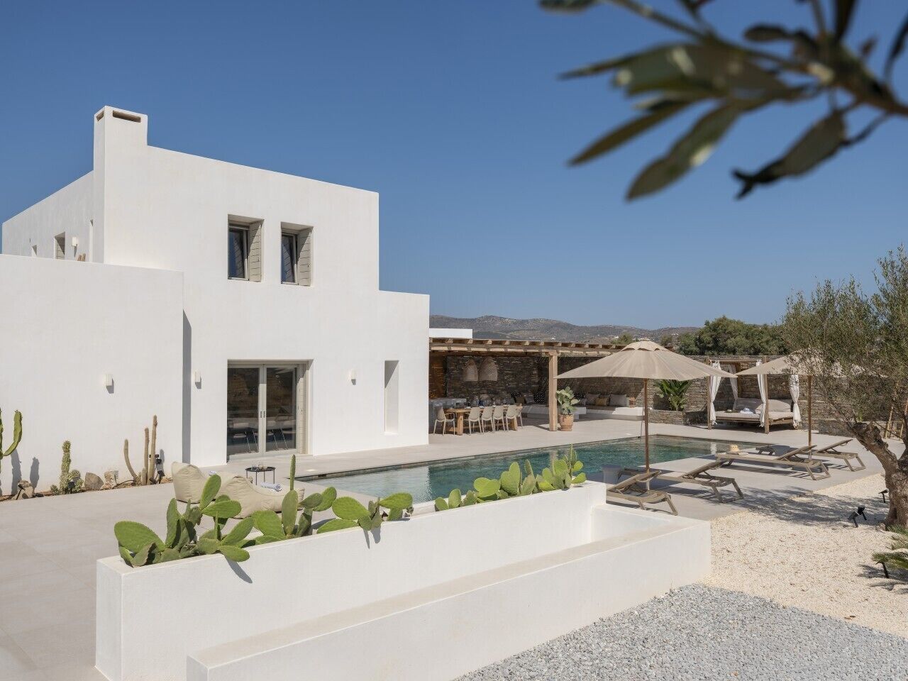 Edificio moderno blanco con piscina, asientos exteriores y cactus.