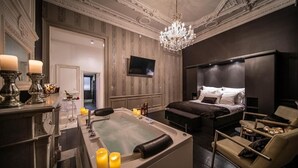 Ein luxuriöses Schlafzimmer mit einem großen Bett, einer Badewanne und einem Chandelier.