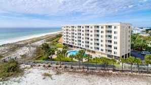 A beachfront hotel with multiple balconies, a swimming pool, and a beach access walkway. - Beautiful Destin on the Gulf 506 w/Beach Service (Destin)