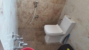 A bathroom with a toilet, shower, and a bucket. - Affordable Cozy Stay for Families Budget friendly (Kommaghatta)