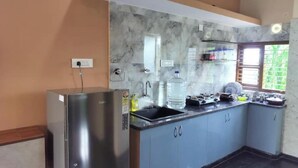 A kitchen with a built-in refrigerator, a sink, and a window with a view of greenery. - Affordable Cozy Stay for Families Budget friendly (Kommaghatta)