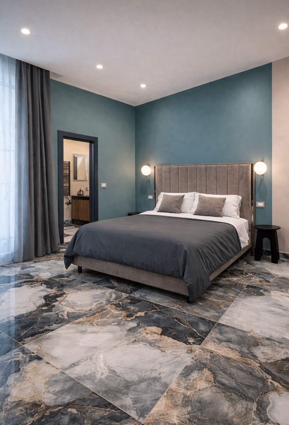 Ein Schlafzimmer mit einem Bett, einem Nachttisch, einer Wandleuchte und einem durch eine offene Tür einsehbaren Badezimmer.