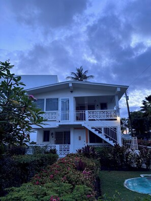 A two-story building with a balcony, a staircase, and a pool.