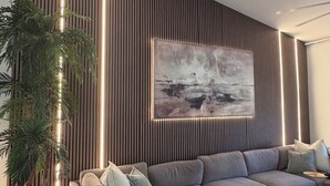 A modern living room with a grey sofa, a coffee table, and a large abstract painting on the wall. - Perfect Snowbird Retreat – Sunny Condo Near Pool & Clubhouse (Naples)