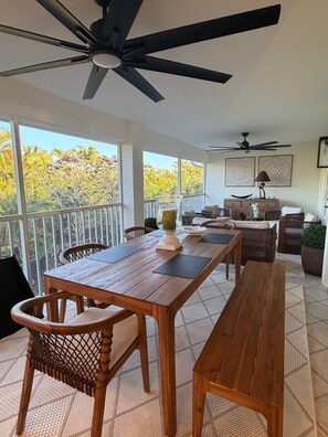 A spacious balcony with a wooden table, chairs, and a ceiling fan. - Perfect Snowbird Retreat – Sunny Condo Near Pool & Clubhouse (Naples)