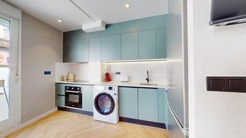 A compact kitchen with a washing machine, oven, and a small countertop.