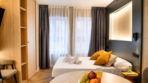 Een hotelkamer met een bed, een stoel, een tafel met fruit en een televisie.