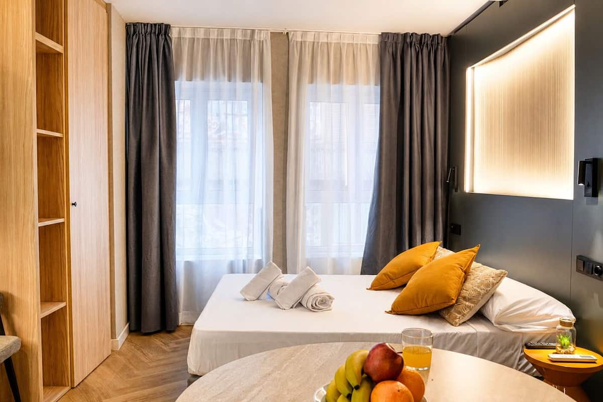 Una habitación de hotel con cama, una silla, una mesa con fruta y un televisor.