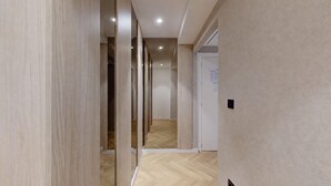 A corridor with wooden paneling, a wooden floor, and a door at the end. - MyFlats La Marina (Alicante)