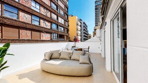 Een modern appartement met een gebogen bank, een eethoek en uitzicht op omliggende gebouwen.