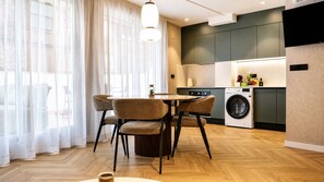 A modern kitchen with a washing machine, a dining area with chairs, and a large window with sheer curtains. - MyFlats La Marina (Alicante)