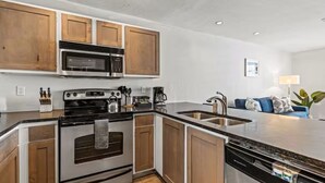 A modern kitchen with wooden cabinets, stainless steel appliances, and a built-in dishwasher. - Lively 2 BR Apt Downtown ATX (Austin)