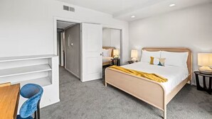 A hotel room with a bed, bedside tables, a desk, and a chair. - Lively 2 BR Apt Downtown ATX (Austin)