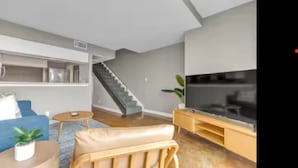 Una sala de estar moderna con una escalera, un televisor y un sofá.