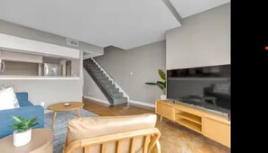 Ein modernes Wohnzimmer mit Treppe, Fernseher und Sofa.