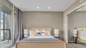 A modern hotel room with a large bed, bedside tables, and a view through a glass door. - Perfectly Located - Cool 2 BR Apt - Downtown ATX (Austin)