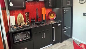 A modern kitchen with black cabinets, a red backsplash, and a black refrigerator.