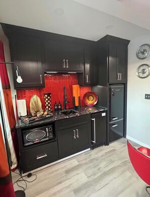 Eine moderne Küche mit schwarzen Schränken, einer roten Spritzschutzwand und einem schwarzen Kühlschrank.