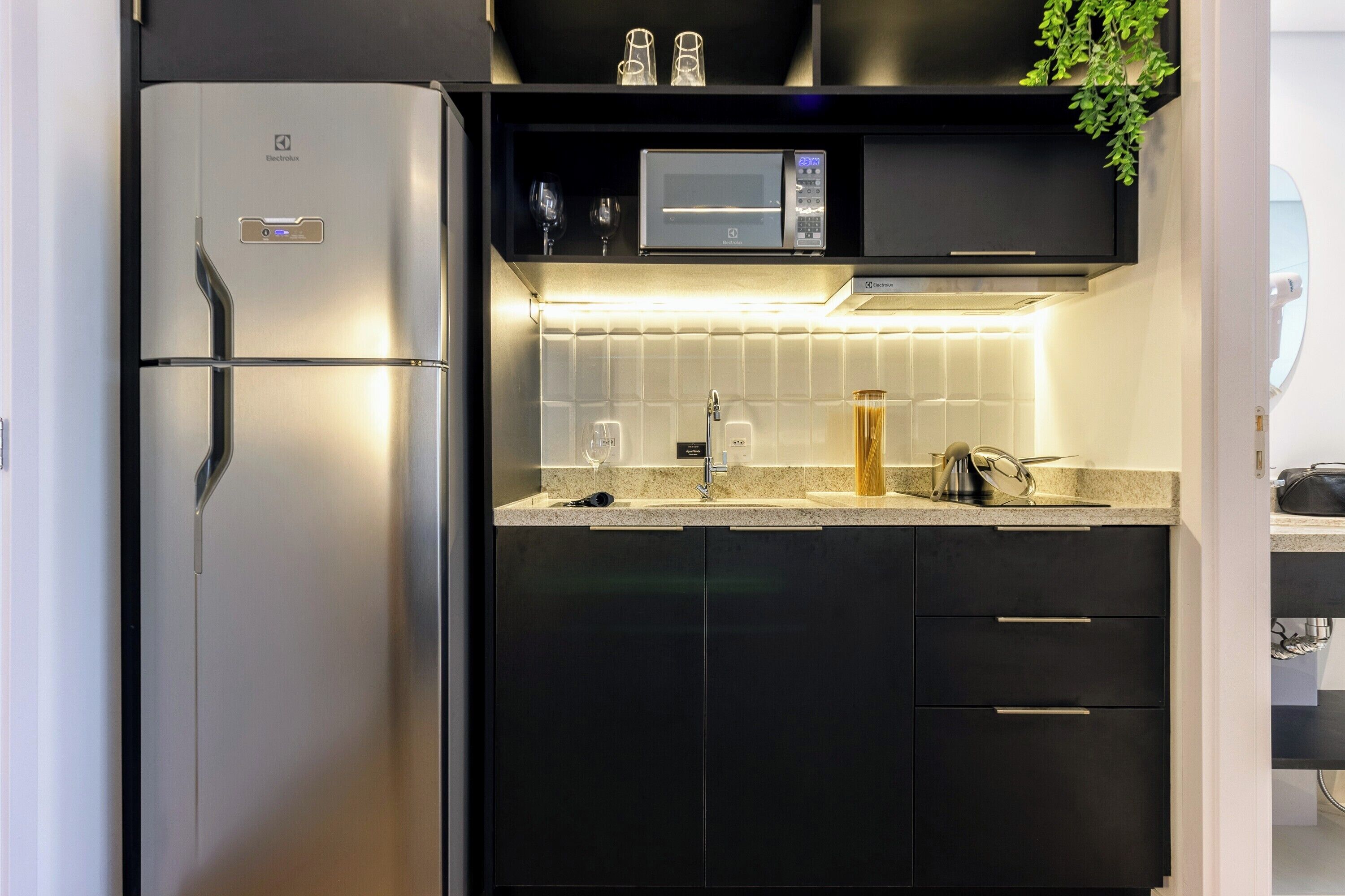 Eine kompakte Küche mit Kühlschrank, Mikrowelle und Einbauofen.