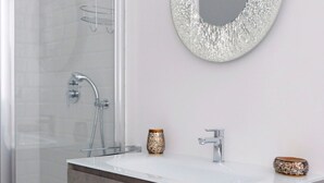 A bathroom with a glass shower enclosure, a white sink with a marble countertop, and two decorative vases. - Hostmate - Milano - Vespri Siciliani - India (Milan)