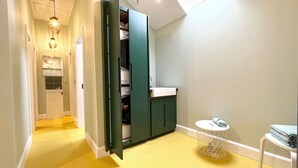 A compact kitchen with a built-in washing machine, a small sink, and a round table with a basket.