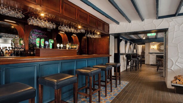 A bar area with stools, a counter with bottles, and a patterned floor.