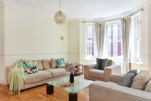 A living room with two sofas, a glass coffee table, and a chandelier. - Fitzrovia Oxford Street Exclusive - 1ES (London)