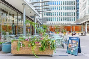 A wooden planter with greenery and flowers, outdoor seating, and a sign for 'CABANA PRE THEATRE DINING'. - Fitzrovia Oxford Street Exclusive - 1ES (London)