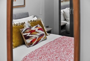 A hotel room with a bed, a nightstand, and a mirror.