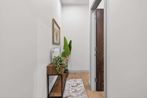 A hallway with a wooden console table, a potted plant, and a framed picture on the wall.