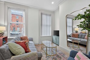 A modern living room with a grey sofa, a coffee table, and a television on a cabinet.