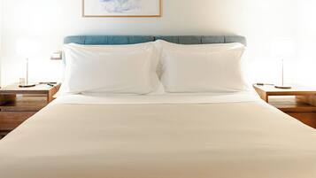 A neatly made bed with white linens, a blue headboard, and two bedside tables with lamps.