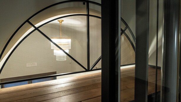A room with a wooden floor, a black-framed window, and a hanging light fixture. - Club64  (Andria)