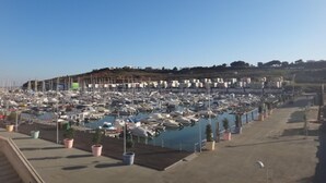 A marina with numerous boats docked, a clear sky, and a hilly landscape in the background. - Sea and Sun Set view (Albufeira)