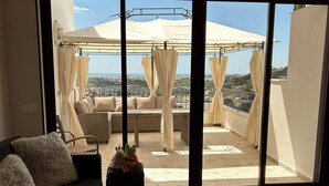 A balcony with a covered seating area, a sofa, and a small table with a decorative item. - Sea and Sun Set view (Albufeira)