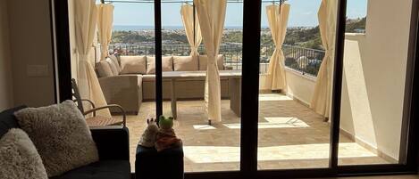 A balcony with a covered seating area, a sofa, and a small table with a decorative item.