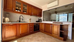 A kitchen with wooden cabinets, a built-in oven, and a large window. - Sea and Sun Set view (Albufeira)