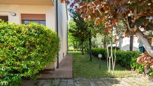 A paved pathway leading to a building with a large hedge on one side and a tree with autumn leaves on the other. - Apartment 'Casa Levanella' with Private Garden (Montevarchi)